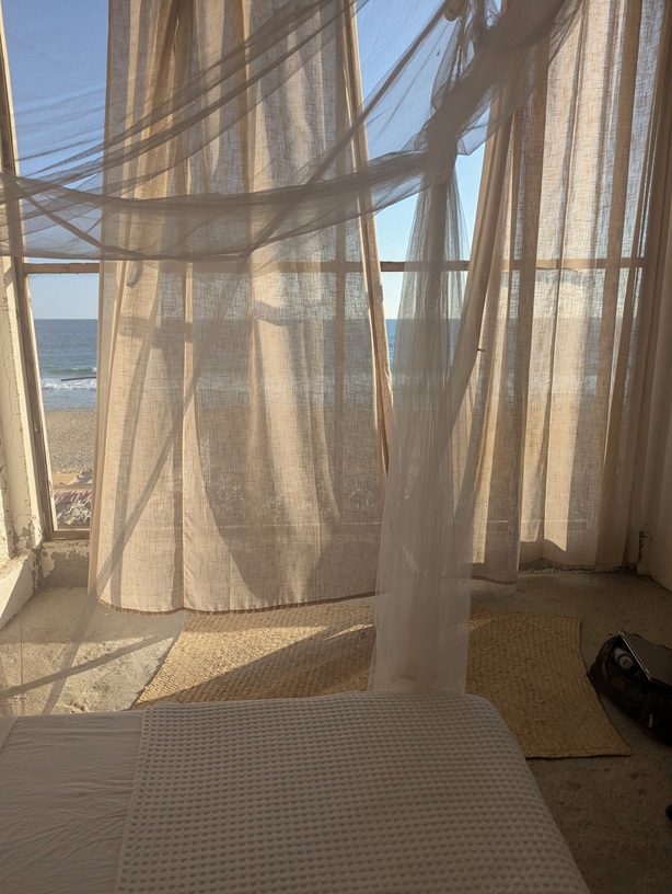 Sheer curtains lightly obscuring a screen looking out over the ocean